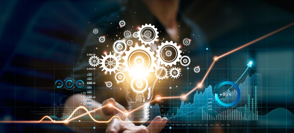 Symbolbild: Geschäftsmann mit Glühbirne. In der Glühbirne leuchtet ein Zahnrad, drumherum stehen Diagramme.
