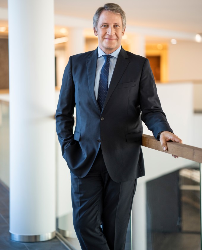 Das Foto zeigt den Amprion-CEO Dr. Brick. Er lehnt an ein Geländer und lächelt in die Kamera.